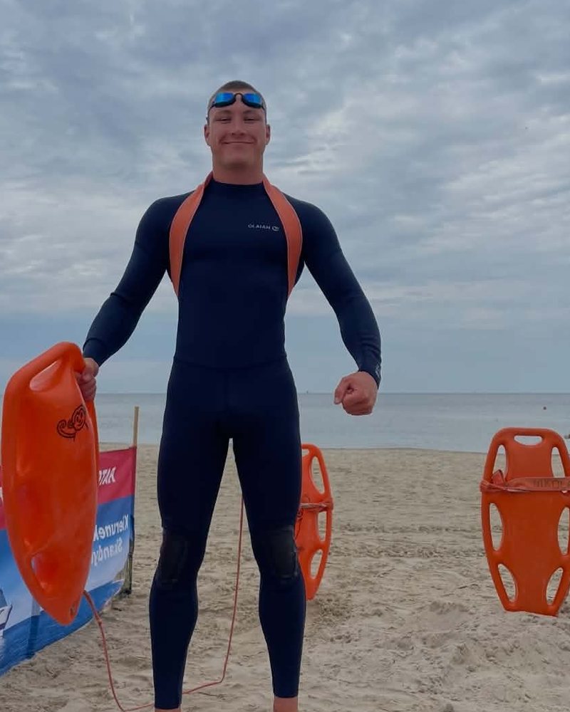 Kuba Strządała w piance na plaży z bojką ratowniczą